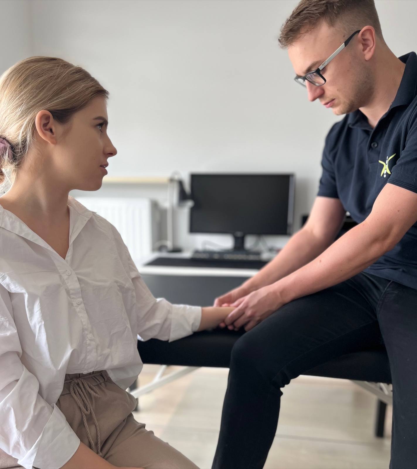 Physiotherapeut behandelt eine Mitarbeiterin direkt am Arbeitsplatz im B&uuml;ro